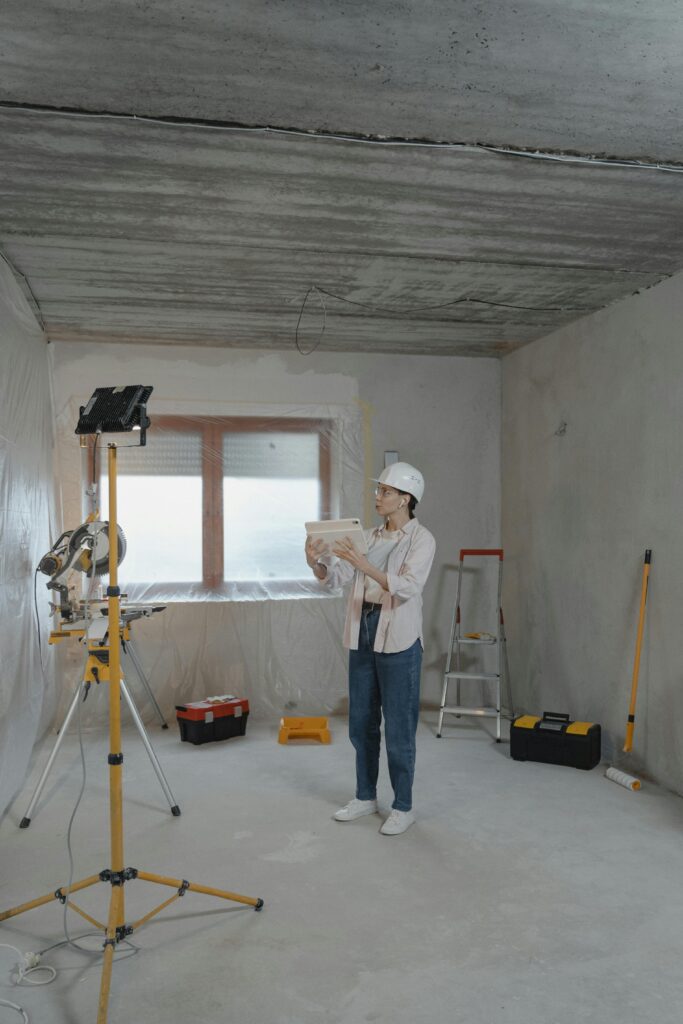 Pexels photo 6474507 6474507 Woman with hard hat and tablet assessing a residential renovation site.