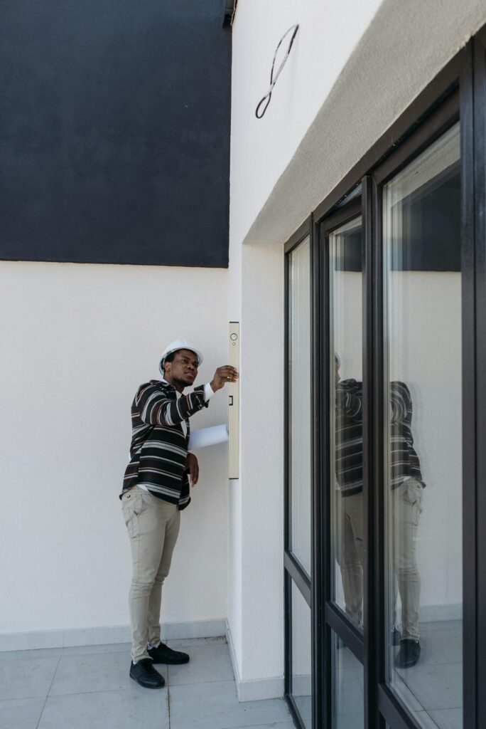 Pexels photo 7937757 7937757 Architect with hard hat inspecting glass doors in a modern building outdoors.