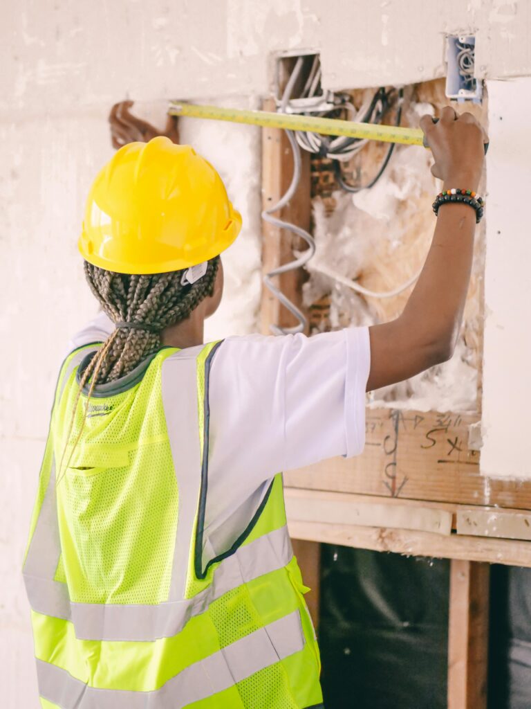 Pexels photo 8488023 8488023 Back view of a construction worker measuring wall space wearing safety gear.