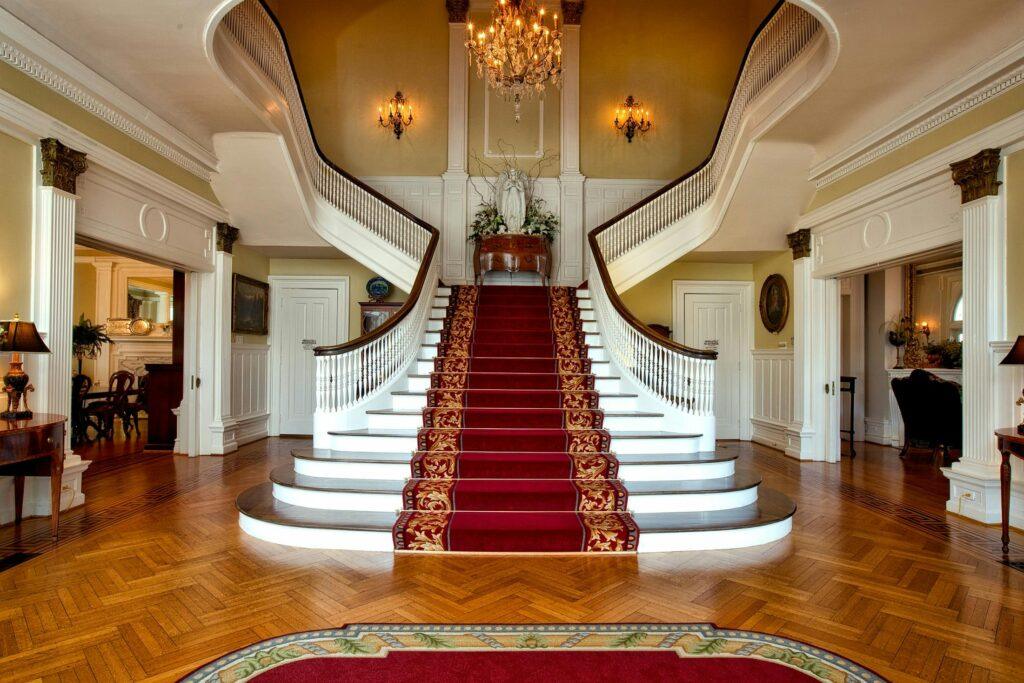 Governor-s-mansion-montgomery-alabama-grand-staircase-161758-161758 Grand staircase with red carpet in a luxurious hotel lobby, highlighted by a chandelier.