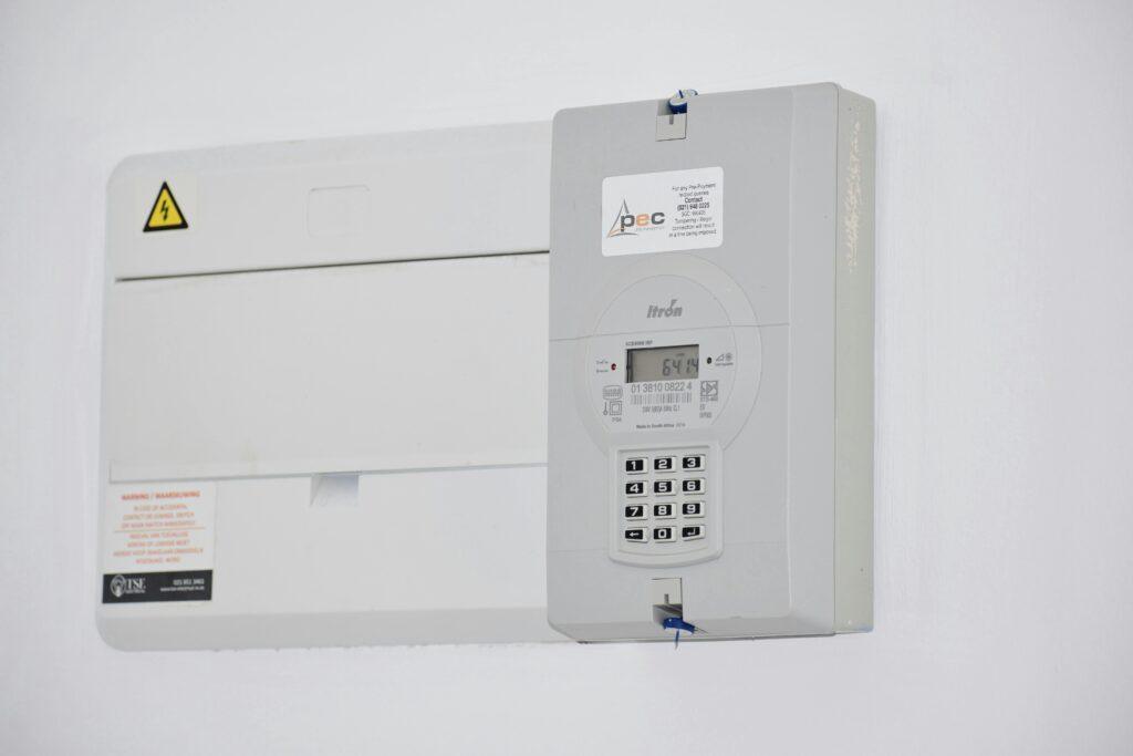 Electrical meter and fuse box on a white wall in cape town, south africa, for energy monitoring or billing.